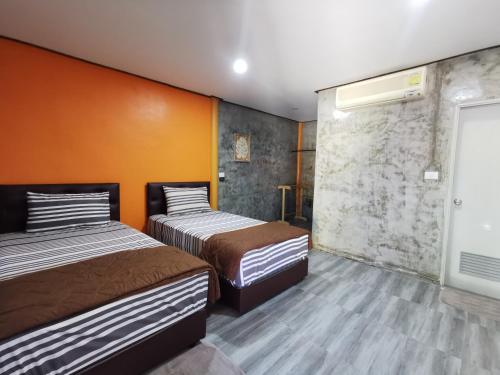 2 camas en una habitación con paredes de color naranja en Viman Resort en Chon Buri