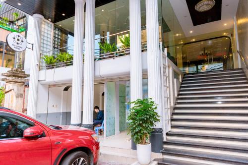 une voiture rouge garée devant un bâtiment dans l'établissement The Opera Hotel Hải Phòng, à Hai Phong