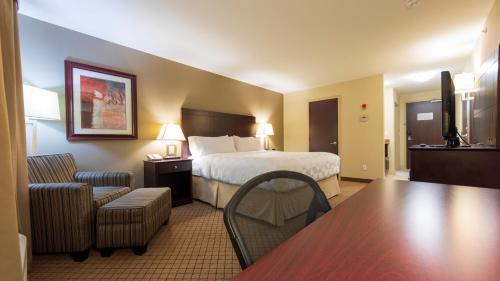 カムループスにあるHoliday Inn Hotel and Suites-Kamloops, an IHG Hotelのベッド、テーブル、椅子が備わるホテルルームです。