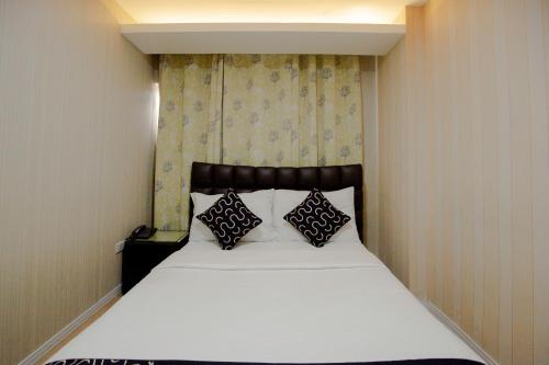 a bedroom with a white bed with two pillows at Newgrange Condotel in Manila