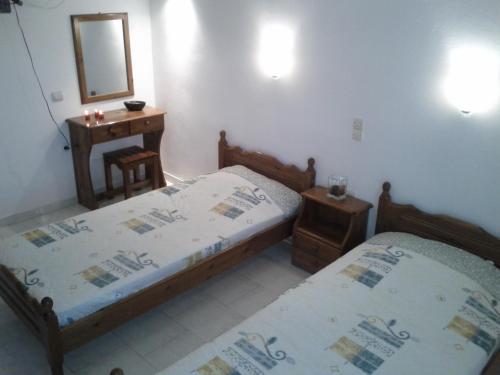 una camera da letto con due letti, un tavolo e uno specchio di Villa Stefania ad Acharavi