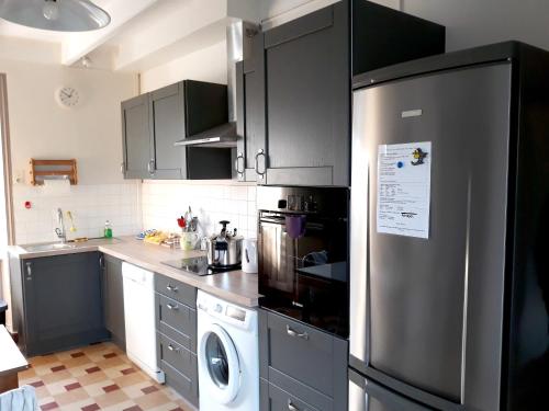 a kitchen with a refrigerator and a washing machine at Maison confortable à Plehedel avec cheminée in Pléhédel