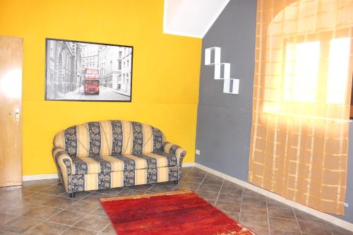 a living room with a chair and a yellow wall at 2 bedrooms house with furnished terrace at Noto 6 km away from the beach in Noto