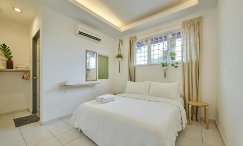 a bedroom with a white bed and a window at Sleepy Nomad Guesthouse in Malacca