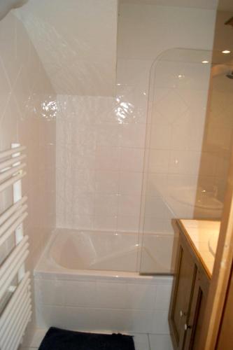 une salle de bain blanche avec une baignoire et un lavabo dans l'établissement Appartement accueillant à Pralognan-la-Vanoise avec balcon et vue, à Pralognan-la-Vanoise