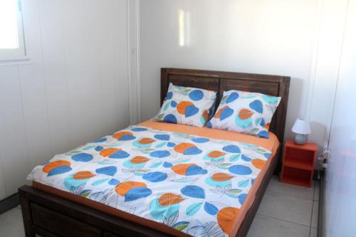 1 dormitorio con 1 cama con edredón naranja y azul en Maison d'une chambre avec vue sur la mer jardin clos et wifi a Petite Ile a 2 km de la plage, en Petite Île