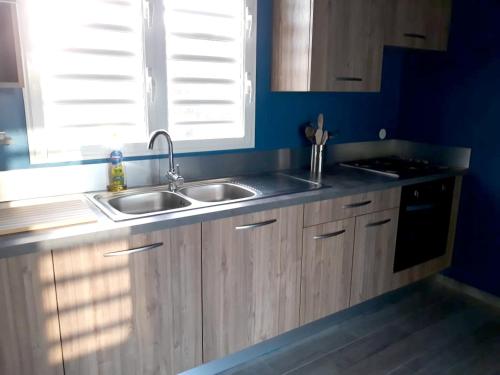 a kitchen with wooden cabinets and a sink and a window at Villa charmante au Moule avec piscine in Le Moule