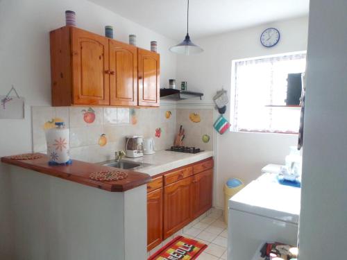a small kitchen with wooden cabinets and a sink at Maison charmante à Bouillante + Jardin in Bouillante