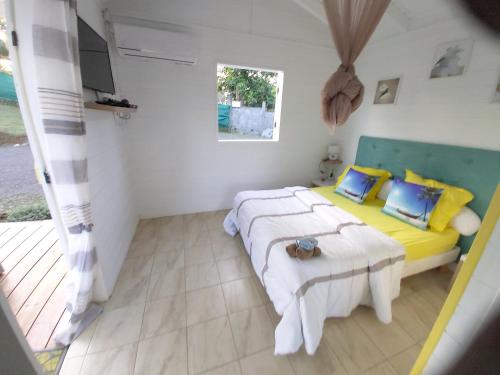 a bedroom with two beds with yellow and blue pillows at Bungalow d'une chambre avec piscine privee jardin clos et wifi a Sainte Rose in Sainte-Rose