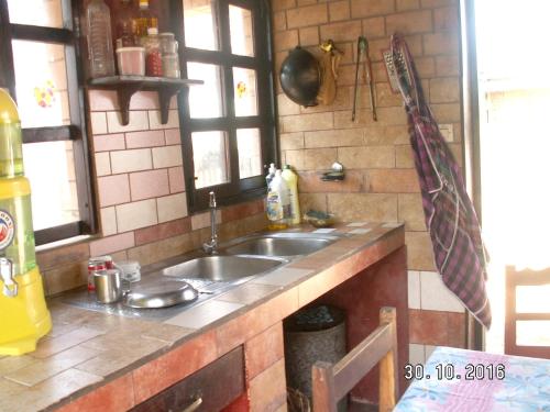 a kitchen with a sink and two windows at 4 bedrooms house at Toamasina 50 m away from the beach with sea view and enclosed garden in Toamasina