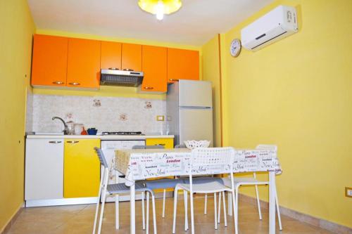 eine Küche mit orangefarbenen Schränken sowie einem Tisch und Stühlen in der Unterkunft 2 bedrooms appartement at Capaccio Paestum 600 m away from the beach with enclosed garden and wifi in Capaccio-Paestum