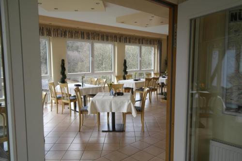 a dining room with tables and chairs and windows at Hotel Pit Lane "Home of Motorsport" in Nürburg