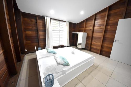 - un lit blanc dans une chambre dotée de murs en bois dans l'établissement Maison de 2 chambres avec sauna jardin clos et wifi a Sainte Anne a 5 km de la plage, à Sainte-Anne