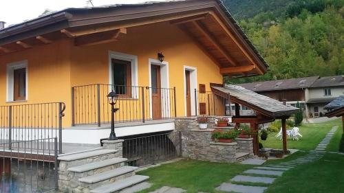 a yellow house with a staircase and a balcony at One bedroom appartement with enclosed garden and wifi at Aymavilles 7 km away from the slopes in Aymavilles