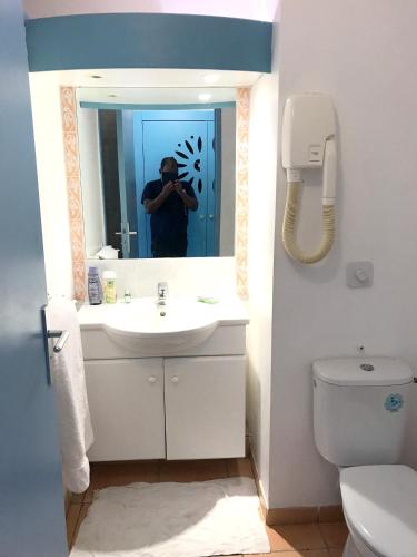 a man taking a picture in a bathroom mirror at Studio a Sainte Anne a 130 m de la plage avec terrasse in Sainte-Anne