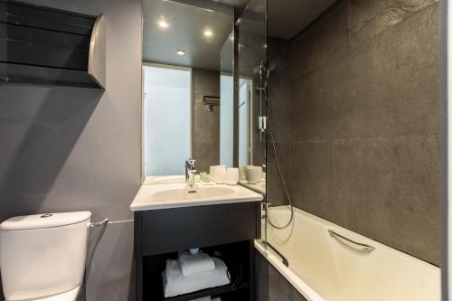 a bathroom with a sink and a toilet and a mirror at Totem, Friendly Hotel & Spa in Flaine