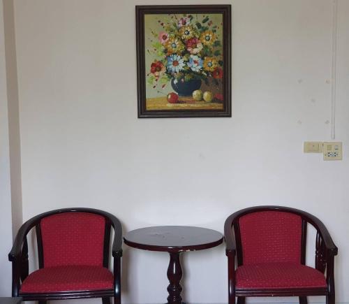 two chairs and a table with a painting on the wall at Matini Amata in Ban Hua Phai