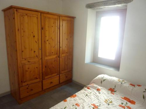 1 dormitorio con armario de madera junto a la cama en Appartement d'une chambre avec vue sur la mer a Bonifacio, en Bonifacio
