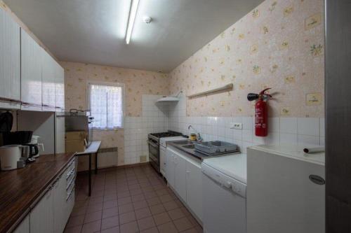 une cuisine équipée d'appareils blancs et d'un extincteur rouge dans l'établissement Maison spacieuse à Nevoy avec jardin de 200 m², idéal pour groupes !, à Nevoy