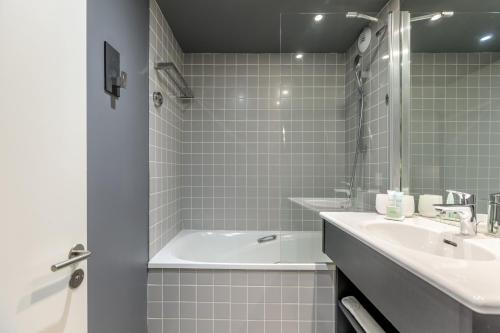 a white bathroom with a tub and a sink at Totem, Friendly Hotel & Spa in Flaine