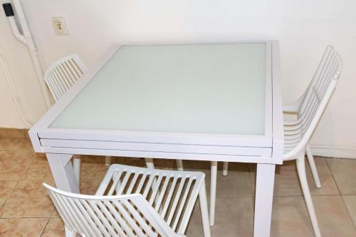 a white dining room table with two white chairs at Studio élégant à Baie Mahault de 19 m² avec balcon et parking in Baie-Mahault