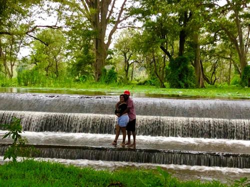 a couple standing in front of a waterfall at Wilpattu Green Cabin in Achchamulai