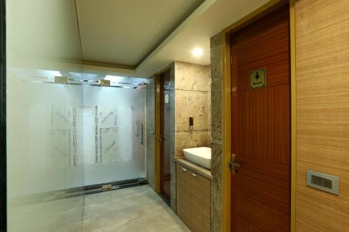 a bathroom with a glass shower and a sink at Hotel Omega - Gurgaon Central in Gurgaon