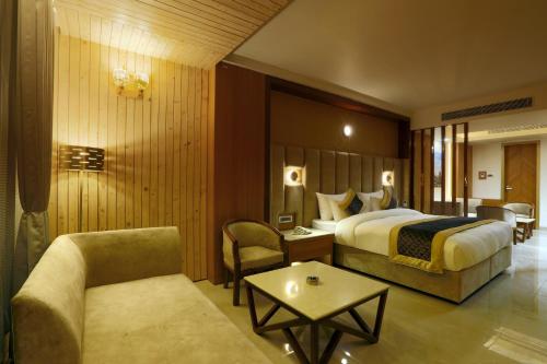 a hotel room with a bed and a couch and a table at Hotel Omega - Gurgaon Central in Gurgaon