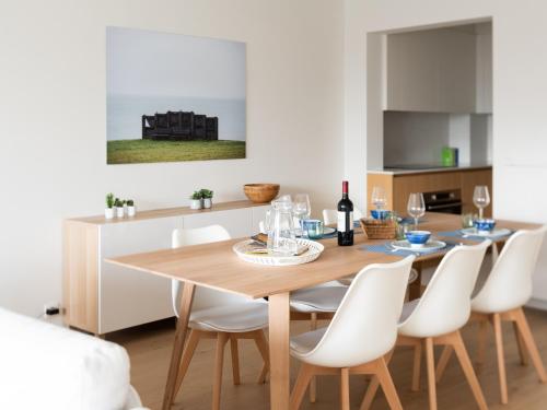 a dining room with a wooden table and white chairs at Modern & spacious apartment near beach in Knokke in Knokke-Heist