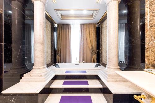 a bathroom with a bath tub and columns at Rixos Khadisha Shymkent in Shymkent