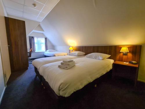 two beds in a hotel room with towels on them at Hotel Eckhardt in Uithuizen