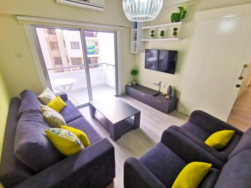sala de estar con sofá púrpura y almohadas amarillas en Beach-a-Holic Apartment, 2 min distance from Larnaca Marina, en Lárnaca
