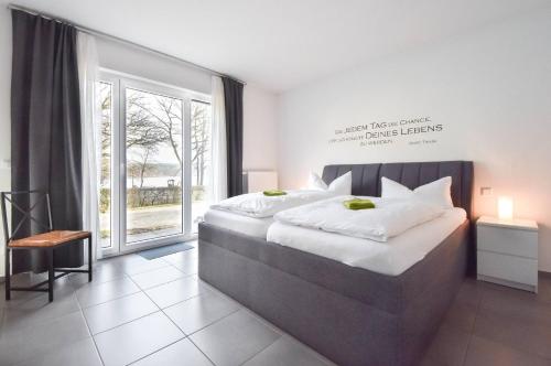 a bedroom with a large bed and a large window at Villa Kaja Wohnung Kaiserbad in Korswandt