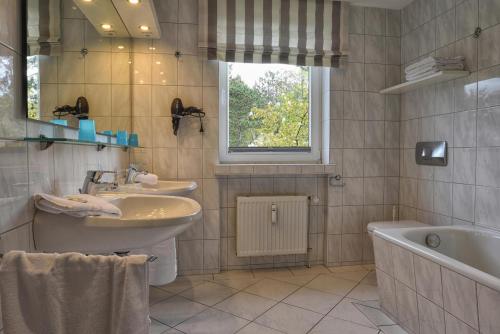 a bathroom with two sinks and a tub and a window at Haus Halligblick Wohnung 18 in Wyk auf Föhr