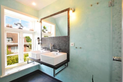 a bathroom with two sinks and a mirror at Auster Hues in Midlum