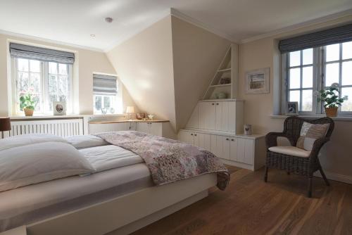 a bedroom with a bed and a chair and windows at Friesenliebe in Borgsum