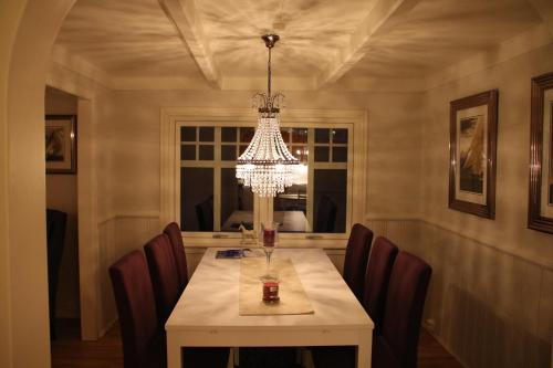 uma sala de jantar com uma mesa com cadeiras e um lustre em Skomakergarden em Ulsteinvik