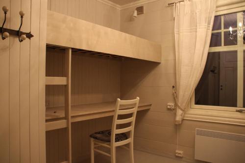 a chair in a room with a shelf and a window at Skomakergarden in Ulsteinvik