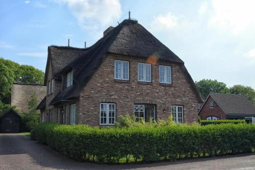 a large brick house with a thatched roof at Gelys Huus in Midlum