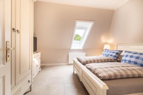 ein Schlafzimmer mit einem Bett mit blauen Kissen und einem Fenster in der Unterkunft Hüs Waalnöd Wohnung 2 in Wyk auf Föhr