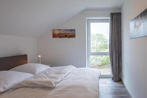 a white bedroom with a bed with a window at Wat een Blick in Nordstrand