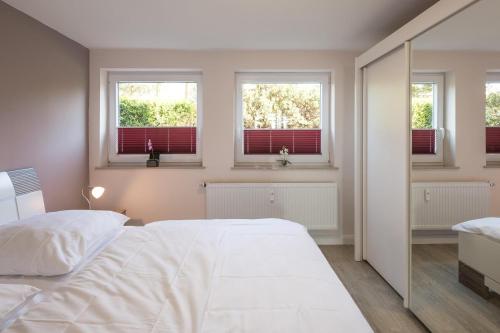 a bedroom with a white bed and three windows at Carpe Diem in Husum