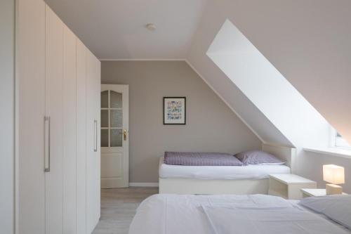 a attic bedroom with two beds and a window at Ferienhaus Marsch auf Föhr in Borgsum