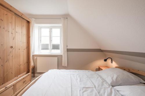 a bedroom with a white bed and a window at Ferienhaus Marsch auf Föhr in Borgsum