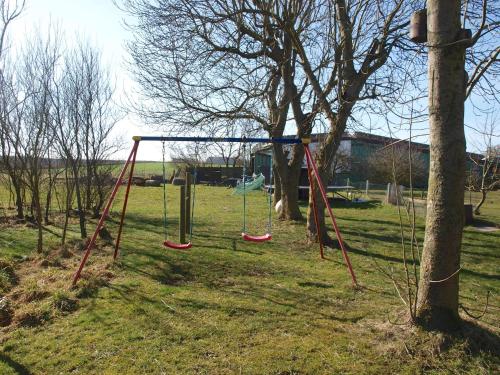 an empty swing set in a park with trees at Ferienhaus Marsch auf Föhr in Borgsum