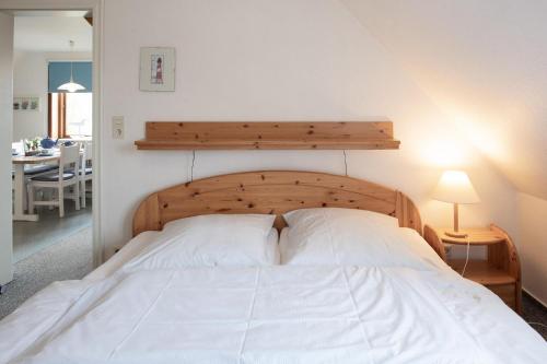 Schlafzimmer mit einem weißen Bett mit einem Kopfteil aus Holz in der Unterkunft Ferienwohnng in Borgsum-oben links in Borgsum