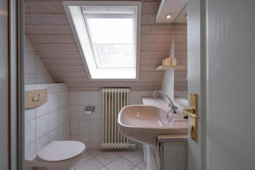 a bathroom with a sink and a toilet and a window at Ferienwohnung in Borgsum (oben rechts) in Borgsum
