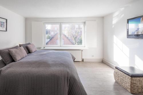 ein weißes Schlafzimmer mit einem Bett und einem Fenster in der Unterkunft Matthis Skipperhuus in Husum