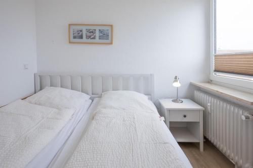 ein weißes Schlafzimmer mit 2 Betten und einem Fenster in der Unterkunft Kleine Perle in Wyk in Wyk auf Föhr