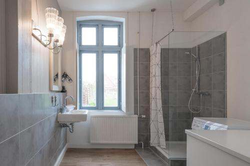 ein Bad mit einem Waschbecken und einer Dusche mit einem Fenster in der Unterkunft Stadthuus 51 in Husum